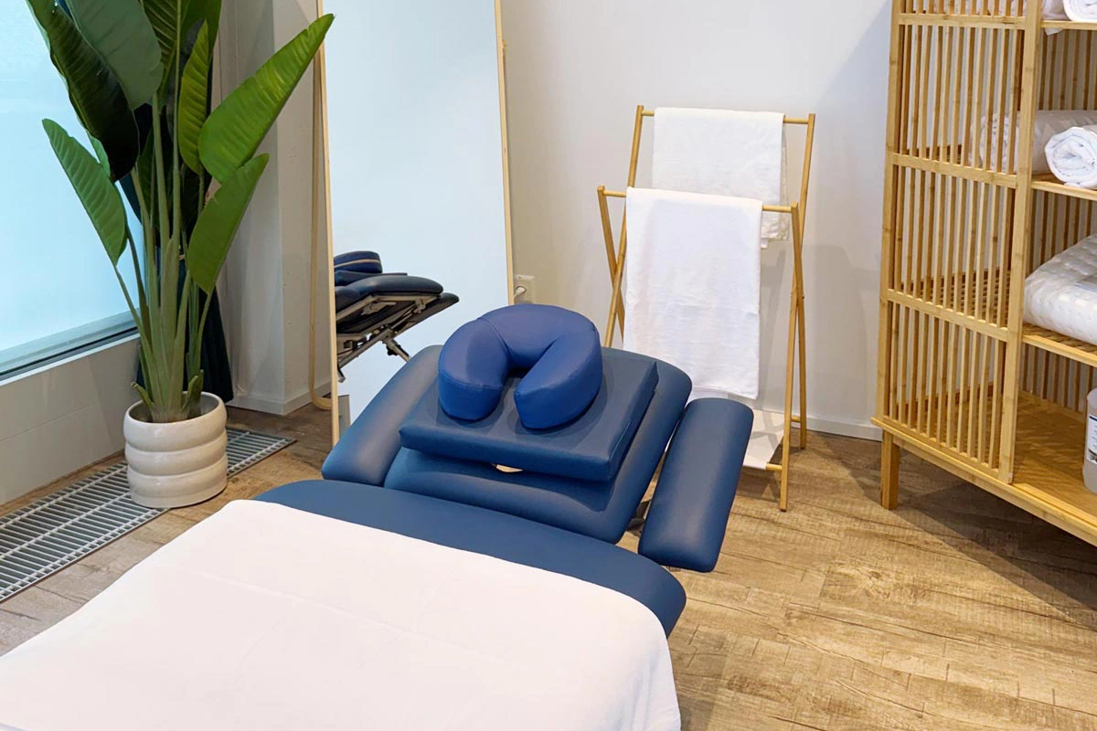 Bezogene Massageliege vor dem Bambusregal mit Frottiertüchern – Praxis des Massage Zentrum Niederhasli in Bülach